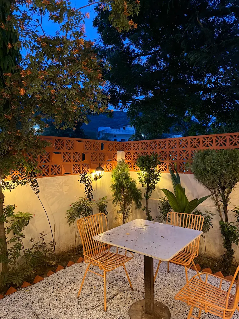 Courtyard seating at dusk beside a terracotta jaali wall
