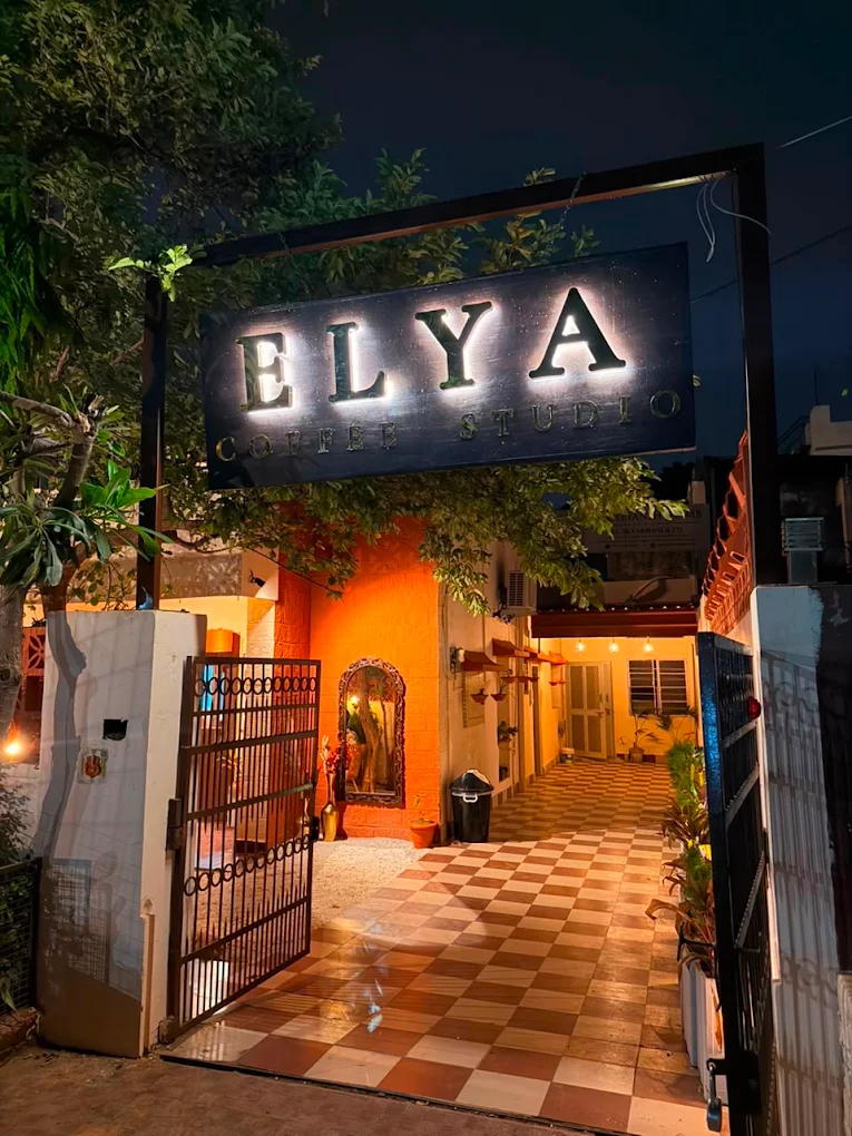 The ELYA Coffee Studio entrance at night, lit warm beneath the trees